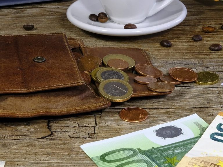 Strom- und Gasversorger wechseln lassen Ein offenes Portemonnaie mit Münzen und Geldscheinen auf einem Tisch, umgeben von Kaffeetassen.