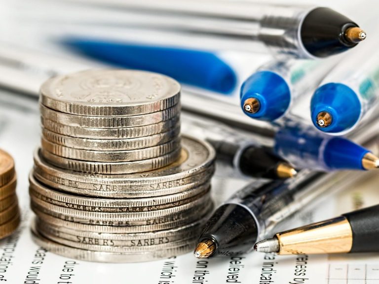Bündelausschreibung Münzen, Papier und Stifte übereinander gelegt