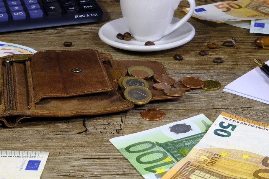 Strom- und Gasversorger wechseln lassen Ein offenes Portemonnaie mit Münzen und Geldscheinen auf einem Tisch, umgeben von Kaffeetassen.