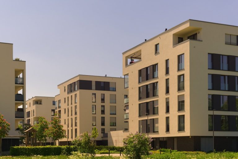 Hausverwaltungen Moderne Wohngebäude mit großen Fenstern und grünen Außenanlagen.